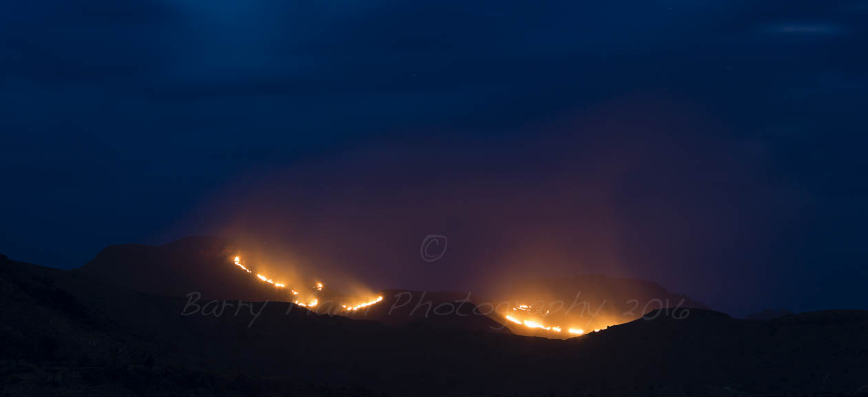 Burning mountains in the Maphutseng Valley, Mohale's Hoek, Lesotho.  Shepherds often burn the mountain sides in Lesotho to promote growth of new grazing for their animals.  Traditionally Basotho shepherds also use fire in this way to call on their ancestral gods to provide rain.